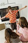 Girl holding a remote control and a boy standing in front of a television