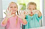 Two girls showing her hands covered with cake icing