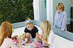 Three girls playing with toys and a boy looking at them