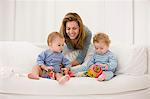 Woman playing with her son and daughter on a couch