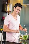 Man mixing vegetable salad in the kitchen