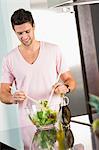 Man mixing vegetable salad in the kitchen