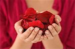 Mid section view of a woman holding a handful of red rose petals