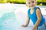 Baby boy leaning on the ledge at the poolside