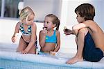 Zwei Mädchen und ein Junge Schokoladen Donuts Essen, am Pool