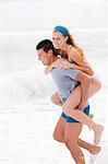 Man giving woman piggyback ride on the beach