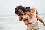 Man giving woman piggyback ride on the beach