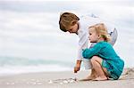 Junge und seine Schwester spielen mit Muscheln am Strand