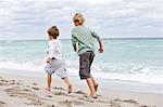 Rear view of two boys running on the beach