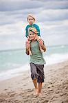 Boy carrying his sister on shoulders on the beach