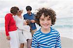 Boy smiling with his family standing behind him on the beach