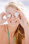 Woman holding shells in front of her eyes