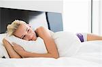 Woman hugging a pillow on the bed