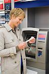 Woman reading a transaction slip at an ATM and smiling