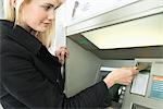 Femme, insertion d'une carte de crédit en ATM