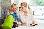 Two women looking in a shopping bag in a restaurant