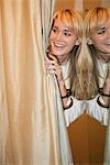 Woman peeking from behind a curtain and smiling in a boutique