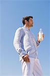 Mann, hält die MilchFlasche am Strand