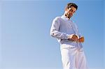 Man buttoning shirt on the beach