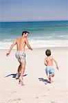 Man running with his son on the beach