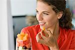 Close-up of a woman eating fruit salad