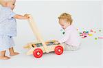 Two baby boys playing with a push cart