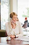 Businesswoman sitting in a restaurant and talking on a mobile phone