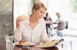 Businesswoman sitting in a restaurant and reading a magazine