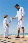 Man giving milk bottle to his son on the beach