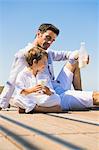 Man and his son drinking milk on the beach