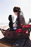 Boy in pirate costume playing with a toy boat