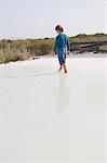 Rear view of a boy walking in an infinity pool