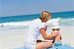 Woman applying suntan lotion on her daughter on the beach