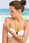 Woman applying suntan lotion on her shoulder