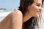 Close-up of a woman sunbathing on the beach and smiling