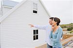 Man pointing towards a house with a woman standing beside her