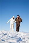 Young couple holding hands, running in snow