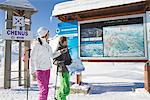 Couple of skiers looking at map, Courchevel, France