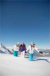 Three teenage girls in ski clothes, walking in snow