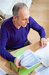 Man holding tax forms and using a laptop