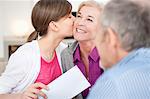 Girl kissing her grandmother with her grandfather sitting beside them