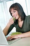 Femme d'affaires manger de germes de soja et à l'aide d'un ordinateur portable