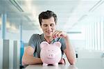 Businessman inserting a coin into a piggy bank