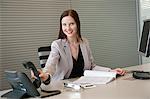 Businesswoman holding a telephone receiver in an office