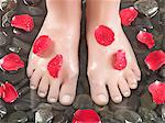 Woman's feet on pebbles, rose petals