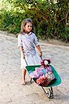 Cute girl pushing a wheelbarrow filled with toys