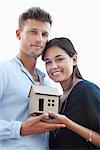 Portrait of a young couple holding small model house