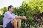 Mid homme adult assis sur un rocher dans un jardin