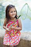 Little girl sitting by the swimming pool with net in hand