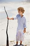 Boy holding a wooden stick on the beach